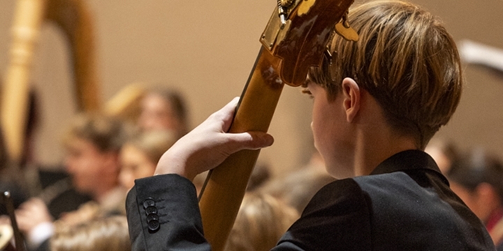 Plakatmotiv tutti pro 2025_Kontrabass Schüler im Konzert mit Orchester im Hintergrund